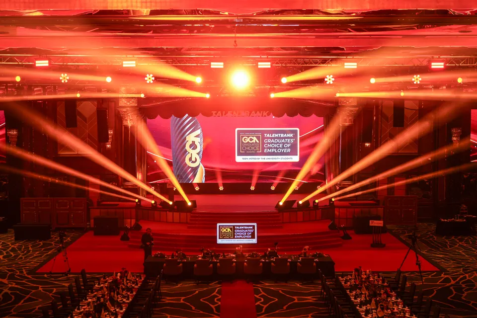 Light beams over a red stage and carpet before a gala begins
