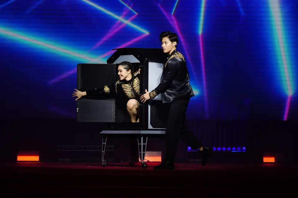 A magic act on stage under laser beams at a gala