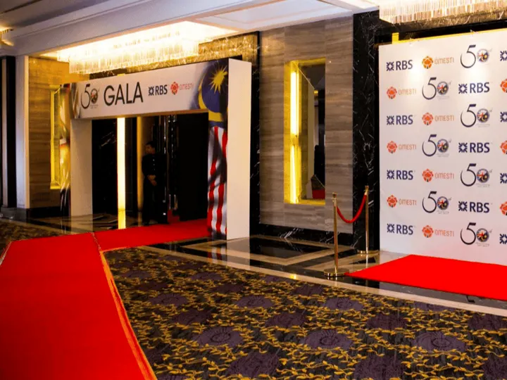 A red-carpeted entrance to a gala dinner, with a gala sign above the doors and a photo backdrop beside them