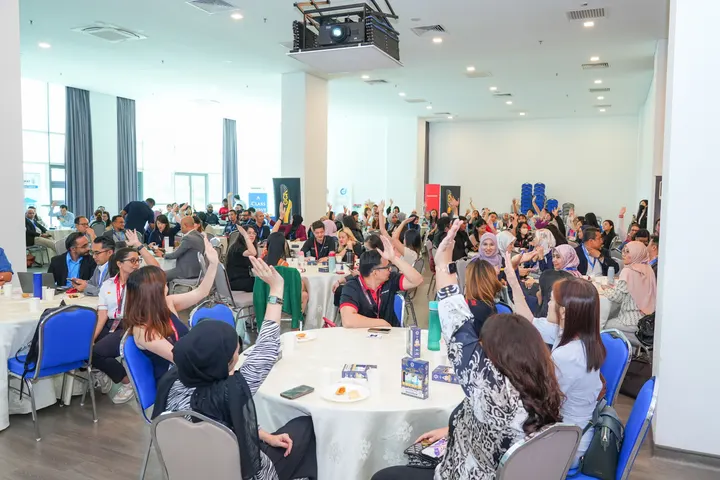 Guests at round tables raising their hands during a dialogue session
