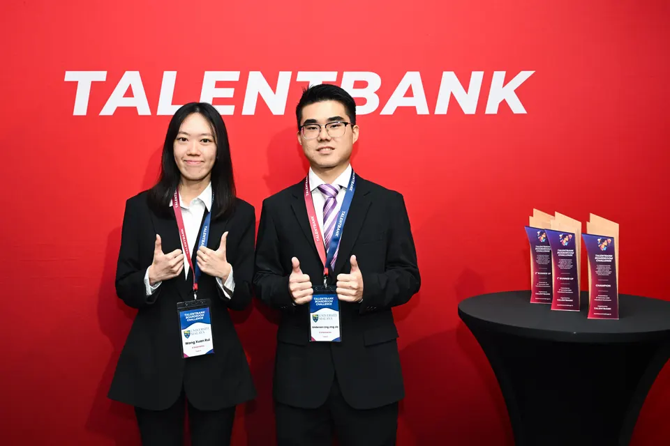 Two finalists giving thumbs up beside the award trophies