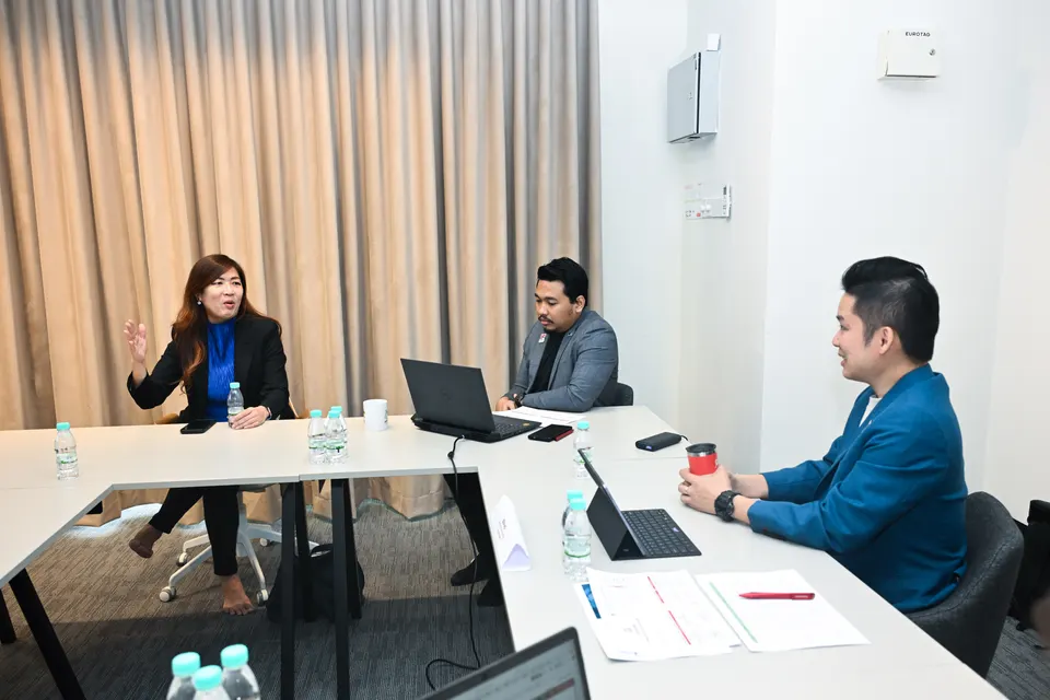 Three judges seated at a meeting table, one speaking while the others listen