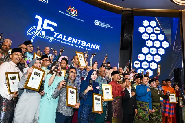 Guests holding framed certificates in front of a stage screen reading Talentbank 15 Years