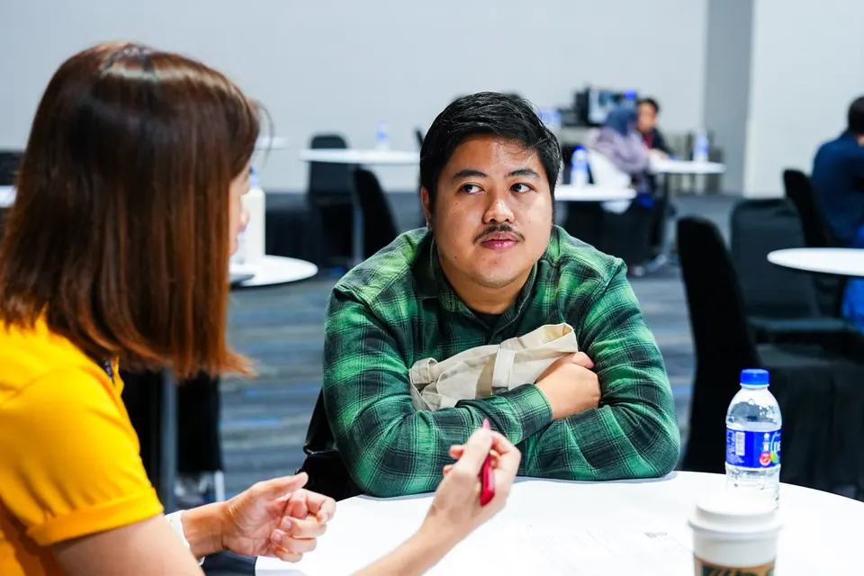 A young man listening to a mentor across a table at the National Career Fair