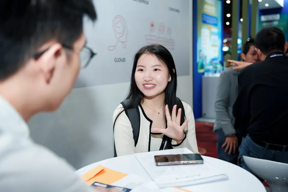 A smiling candidate in conversation with a recruiter at a table
