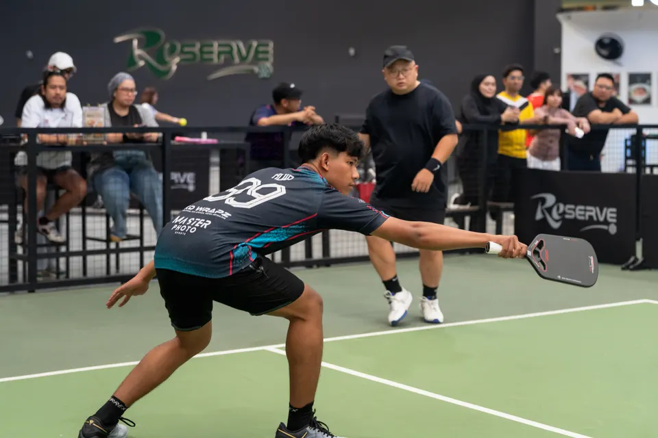A player stretching low to return a shot on a pickleball court