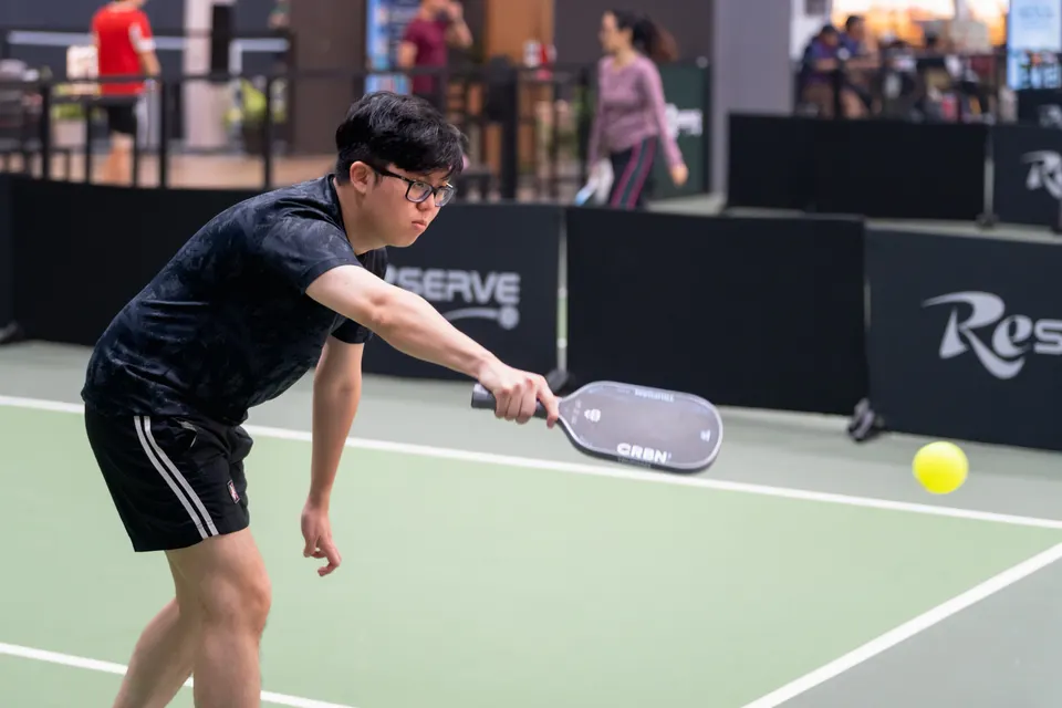 A player reaching low to hit a pickleball