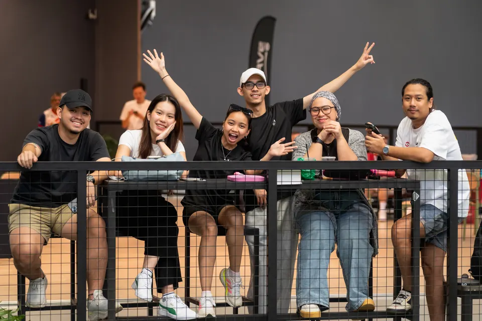Spectators cheering and waving from behind the court fence