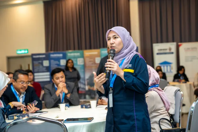 A delegate asking a question to a hall of seated guests at a Talentbank Graduate Recruitment Dialogue