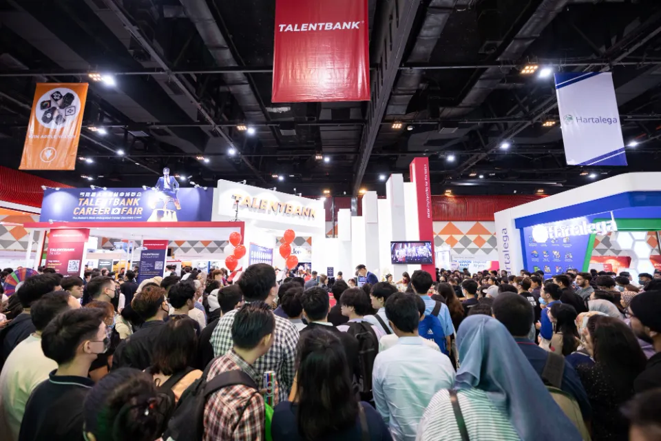 A crowded exhibition hall with employer booths at a Talentbank career fair
