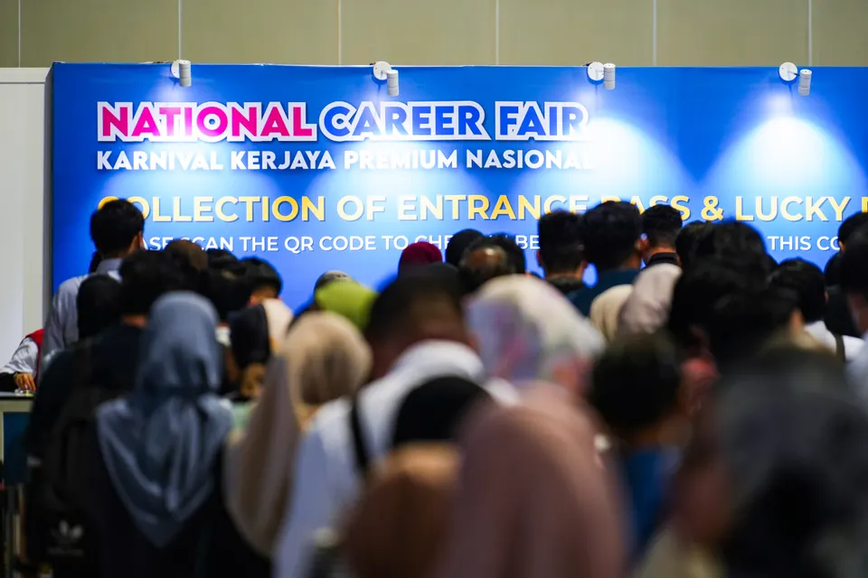 A crowd of candidates gathered in front of the National Career Fair banner