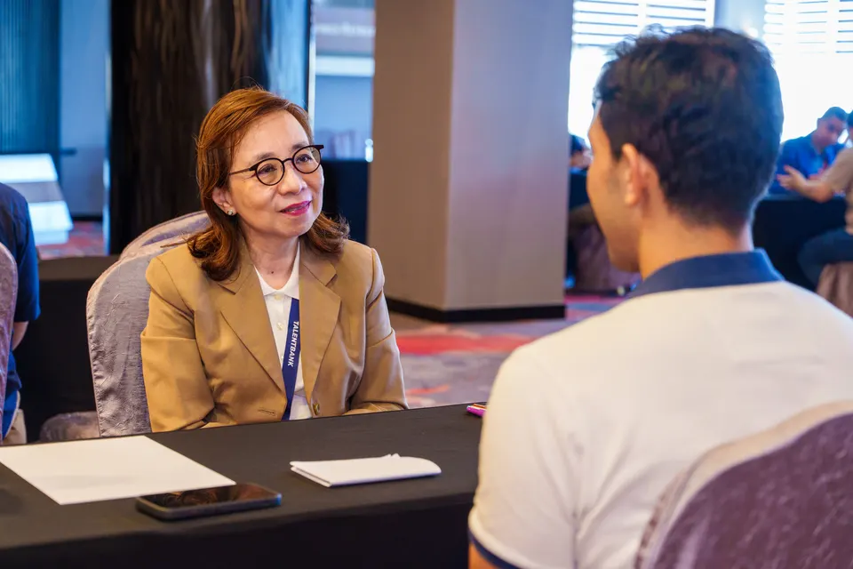 A smiling mentor listening to a visitor at the Talentbank Career Fair 2025
