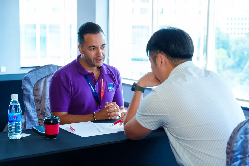 A mentor and a visitor in discussion by the windows at the Talentbank Career Fair 2025
