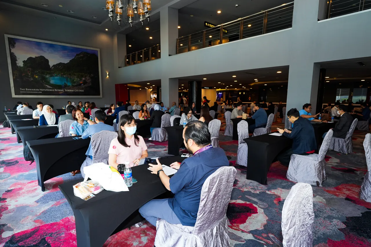 Mentors and visitors in conversation across tables in a hall at the Talentbank Career Fair 2025