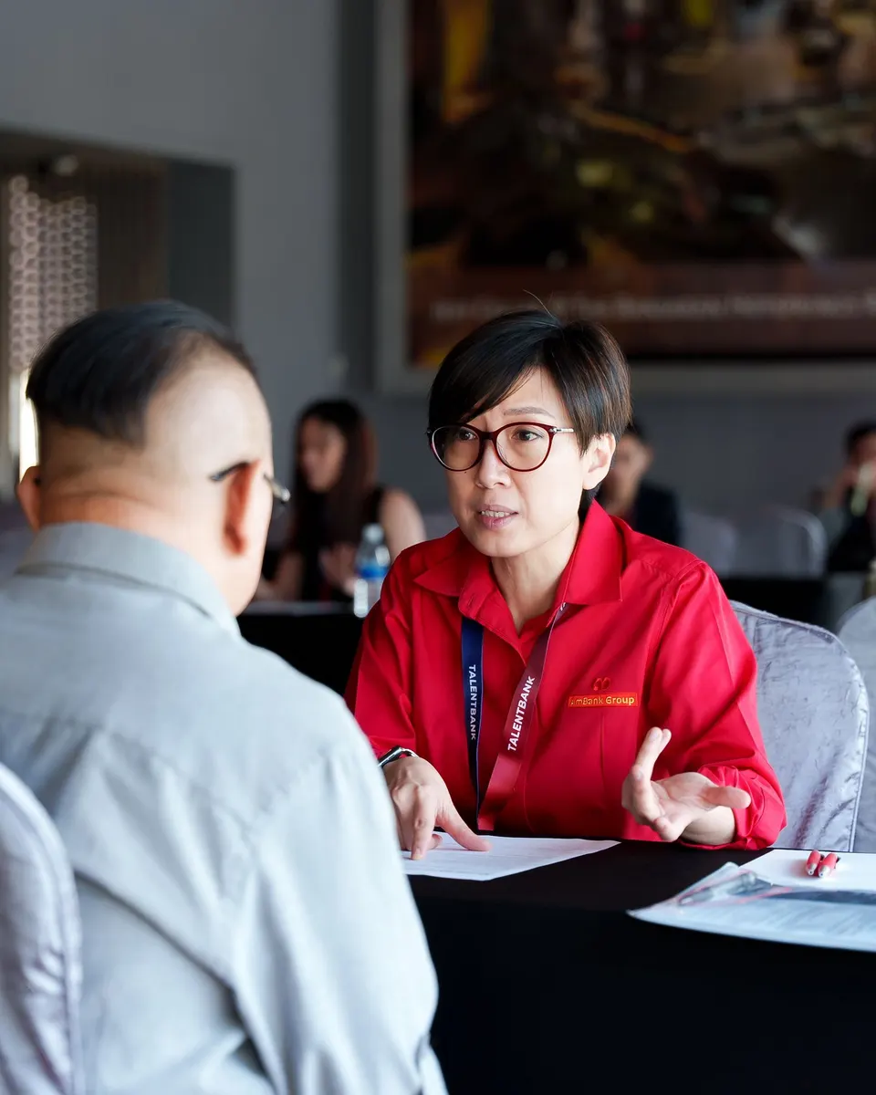 An employer representative in a red shirt talking with a candidate across an interview table at the Talentbank Career Fair