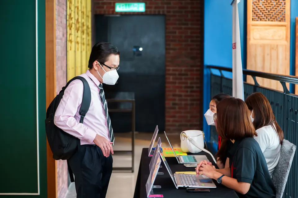 A candidate checking in at a registration desk with laptops