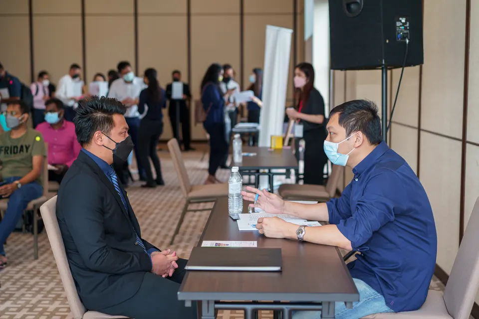 A candidate in an interview with a recruiter while others wait behind