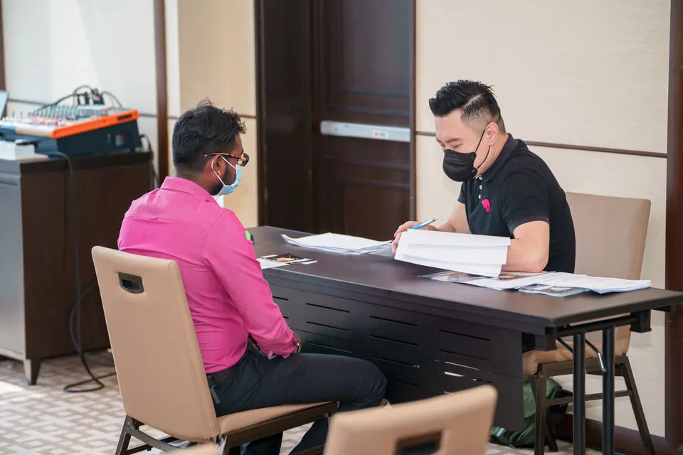 A recruiter reviewing papers with a candidate at an interview table
