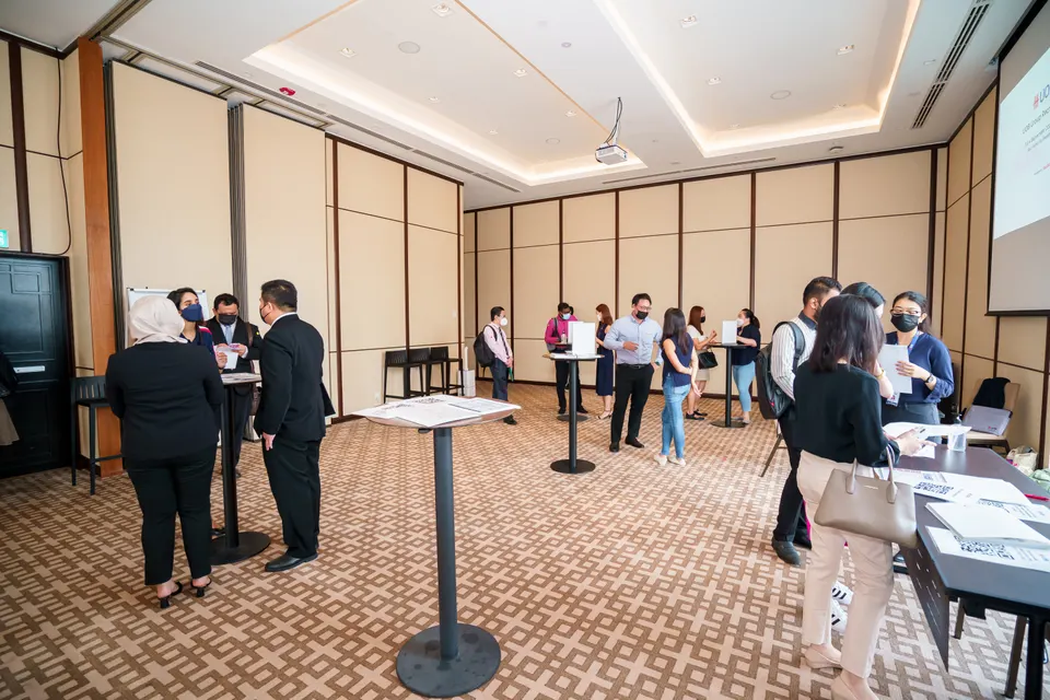 Candidates queueing at standing tables to be seen, in a function room set up for a recruitment drive